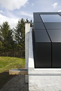 Danish Farmhouse Turned Contemporary Art Studio - Photo 3 of 6 - The contrast between the barn’s original exterior structure and the new architectural elements is a large part of the finished studio’s charm. The aluminium roof peaks out of the existing façade, providing the traditional barn with an air of modernity.