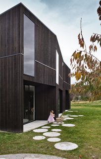15 Modern Homes with Black Exteriors - Photo 13 of 15 - Cooke clad the building in a black-stained, sustainably-grown Canadian cedar, a durable choice that ages well and requires little maintenance. The dark glazing was chosen so windows appear seamless, accentuating the form of the building.