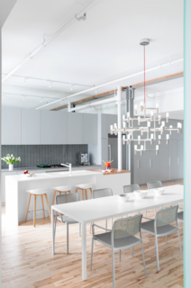 In a 1920s building on St-Dominique Street in Montreal, formerly a factory for canned soup, a sleek apartment for a family now stands. In the open-plan dining area, a Major Crown chandelier by Nemo hangs above a Zeus-Noto table and Kartell chairs. 