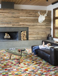 A Custom, LED-Lit Slide Twists Through This Family-Friendly Vacation Home - Photo 3 of 11 - When building their dream retreat in Jackson Hole, Wyoming, Steve and Alexi Conine worked with architect Brad Hoyt to create a smart house that fused technology and design. Like the rest of the home, the living-room furnishings blend high design, comfort, and kid-friendliness, including a table by Isamu Noguchi for Herman Miller, a leather sectional sofa from Four Hands, a cashmere cableknit-covered elk mount by Rachel Denny, and a custom, multicolored cowhide patchwork rug by Linie Design.