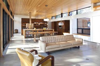 A Serene, Sustainable Home in Colorado - Photo 8 of 10 - Sunlight streams through tall glass panels into the kitchen and living area, while on the opposite wall, a high band of windows top built-in storage, a window seat, and a pizza oven. <br><br>Photo by Ron Johnson.