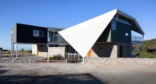 The tent-like form—with an area of 2,150 square feet—extends past the perimeter of the house to shield it from the elements.
