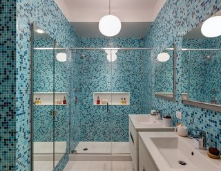 Bold color is embraced in the home’s first bathroom, with tilework by Trend Mosiacs. Faucets are by Grohe and vanities are by Hastings. A Flos Glo-Ball pendant light illuminates the space.