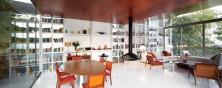 A Modern Concrete Home in Peru - Photo 7 of 13 - A structural steel wall in the living area doubles as a built-in bookcase. The side chairs, floor lamps, and dining chairs were salvaged from the Hotel Crillón in Lima. The daybed and coffee table were designed by Maria Eugenia Alvarez-Calderón, who helped Irzio and Lisette with the interiors. The fireplace is from Fireorb and, as throughout, the floor is poured white acrylic by Química Suiza.