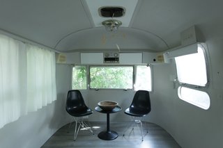 The egg-like living room doubles as the children’s bedroom after dark, thanks to mattresses stored in a custom banquette in the studio area. The sole decorative elements are Eames shell chairs, an Ikea table, and a balsa-like children’s mobile received as a gift.