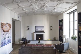 The historic vaulted ceilings were carefully restored by Morris Adjmi Architects in the renovation of the ROOST Apartment Hotel in Philadelphia. They contrast with the modern herringbone wood flooring, plush furniture selection, and clean lines of the built-in shelving and fireplace.