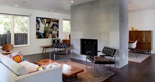 The new living room is open and bright. A hearth sheathed in concrete tile from Sadlerstone—a material that recurrs throughout the interior—is the space's focal point. Much of the vintage furniture came from Retro Inferno.