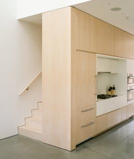 Light streams from above into the living room and kithen thanks to the home's largest skylight. This skylight isn't one large window but two: one on the eastern side of the double-height volume, and one on the western. In between them are sculptural, pyramid-shaped forms that block and diffuse the sunlight throughout the day. In the words of the architects, they "add to the unexpective quality of light" in the space.