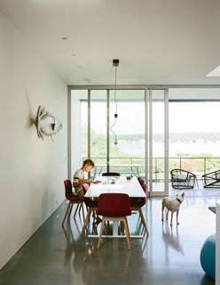 In the home’s west-facing wing oriented toward the pond, Christopher, 10, sits in the dining area, furnished with a Luxor table by Cappellini, chairs by HAY, and a Counterweight pendant by Fort Standard. The fish sculpture is by Mark A. Perry, a local folk artist.
