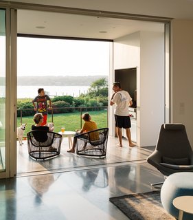 Outside, the deck is equipped with a grill, a concrete dining table by Landscape Forms, chairs by Zanotta, and retractable insect screens from Phantom Screens—a necessity in the humid climate.