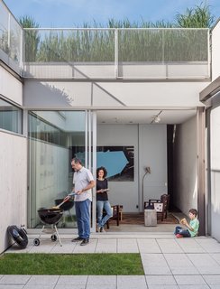 The home’s enclosed courtyard sits at "the heart of the structure," says Baumann, who resides with his wife, Lisa Sardinas, and eight-year-old son, Oskar. "This is clearly the dominant space; everything flexes towards it." Baumann cast the square concrete floor tiles himself, enlisting the help of his son. A small, neat patch of grass—a playful nod to the archetypal domestic lawn—is edited down to a charming folly.