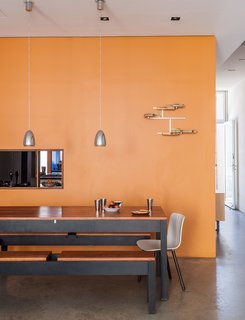 Sheetrock surfaces comprise many of the interior walls, including one situated between the kitchen and dining area, which is furnished by benches and a table designed and built by Baumann, alongside HAL chairs by Jasper Morrison for Vitra.