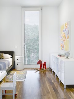 The upper two levels of the home are set back from the street, increasing privacy and allowing light to flow uninhibited from the front clerestory window into the communal living spaces. On the top floor, the children's bedrooms are strategically veiled from the street by the slatted reflector screen.
