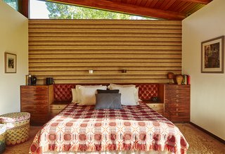 The master bedroom boasts a 1970s tufted headboard from Heals Leather and a wall covering of burlap, wool and silk by David Hicks. The bed covering is vintage, 1950s, and the Blocks linen basket was designed by Donna Wilson and made by the People of the Sun, a nonprofit based in Malawi.