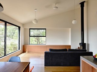 The homeowners wanted a simple, unfussy space. The walls throughout the home are painted in Dulux Swan White. Built-in cabinets are custom made in Tasmanian oak. The hanging pendants are from About Space and the wood-burning stove is a Morsø 7642 model.