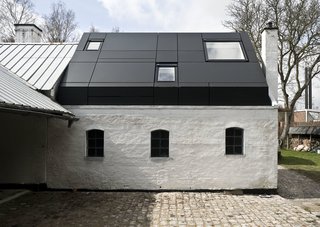 Danish Farmhouse Turned Contemporary Art Studio - Photo 2 of 6 - Although the old window and door openings of the original building remain visible from the exterior, they were covered on the inside with veneer. Instead, large windows on the roof and a clear glass door supply the interior with adequate daylight.