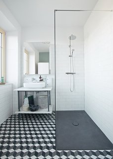 In renovating her home in Schönkirchen-Reyersdorf, Austria, Katharina Reckendorfer repurposed what she could—like a bathtub and vanity—and streamlined the rest. New black and white graphic cement tile from Mosaic del Sur, Hansgrohe fixtures, a shower plate from Bette, and Farrow & Ball’s Chappell Green paint round out the room.