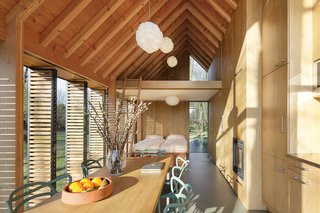 The house's open plan is neatly divided into public and private spaces, with the front containing the kitchen and living areas and the back holding the bedroom and bath, overhung by a small mezzanine. A hidden wooden panel can be drawn closed between the two sections for greater privacy.