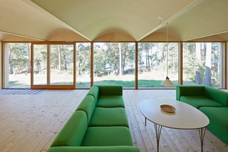 The site faces the sea but is surrounded by tall pines. The green sofas are from Hay.