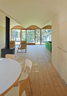 The first floor contains communal rooms (kitchen, living room, etc.) and private sleeping spaces are located above. The dining room table and chairs are from Artek.