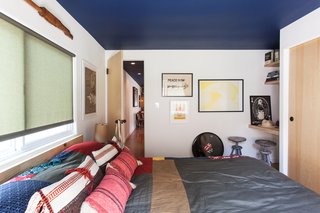 A Modern Beachside Trailer Home in Malibu - Photo 5 of 7 - The blue ceiling continues into the bedroom, filled with art by Howard’s friends. The yellow-and-white poster is by Mike Mills, and the signed Rolling Stones drumhead was a gift. "It feels like a New York apartment at the beach," says Shumate.