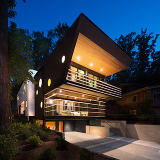 A screened-in porch was a must-have for the residents (they love to sit outside but hate mosquitoes) and influenced the building's asymmetrical shape. "The question became how can we integrate this into the design of a modern house," says architect Staffan Svenson. "Can it be a screen porch without looking like one?" He devised a plan to hang a horizontal louver system from the structure to give the illusion that the powder-coated steel fins hover in place. He used the same material for the guard rail on the second story.