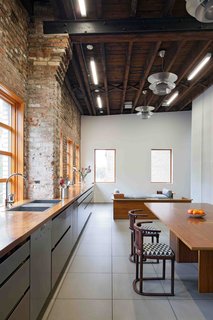 20 Best Modern Kitchen Counters - Photo 9 of 20 - What the original building lacked in period detailing, it made up for with massive interior spaces, natural light, and a hardy palette of wood and raw brick. Working with these loft signatures, David developed the gigantic kitchen on the upper floor running the width of the building, with a 37-foot-long solid walnut counter on top of stainless-steel cabinets. This unites the dining, cooking, and social spaces that run the length of the front facade on the upper floor.