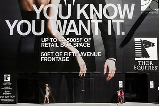 A pair of young gossip girls and a lady walking by a New York City ad.