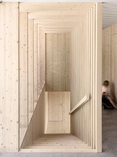 A Simple Gabled House Features an Intricate Latticework Shell - Photo 6 of 10 - An unadorned spruce wood staircase leads to the upper level.