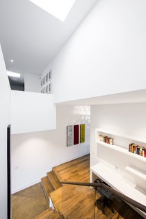 This double-height stairwell, just adjacent to the kitchen, marks the transition from the historic building to the new renovation. A skylight pulls sunlight from above into the home office below.