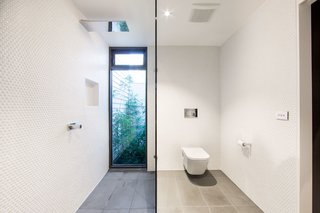 The newly-renovated master bath features white brass fixtures. A small enclosed garden brings natural light into the bath while maintaining privacy.