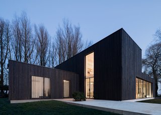 "We wanted the wood to appear as natural as possible, so leaving the larch untreated was the first choice," Bas explained. But the shape of the house would make the wood turn gray unevenly, so they blackened the larch. "The clients were excited with the dark color as it helps the house blend into the trees. They didn’t want the anything excessive or showy." But blackened timber comes with its own challenges. Since it absorbs more heat, a larger air cavity was built behind the wood to keep it cool.