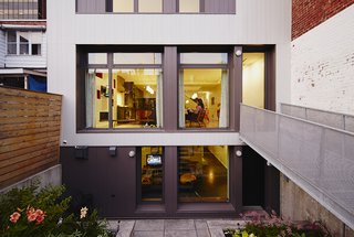 At the rear of the house, exterior steel cladding by Vicwest updates the look of the facade, while a steel footbridge connects the garden to the main floor of the house