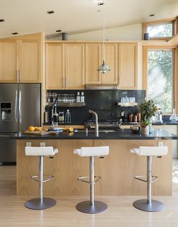 Pam stools from Ligne Roset pull up to the kitchen island; the custom birch cabinetry complements a Caesarstone Raven countertop.