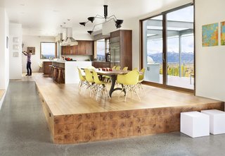 A Custom, LED-Lit Slide Twists Through This Family-Friendly Vacation Home - Photo 4 of 11 - Beams extending from the kitchen floor give the impression of an oversize butcher-block stage for a custom walnut-slab table and a dozen Molded Plastic chairs by Charles and Ray Eames for Herman Miller.
