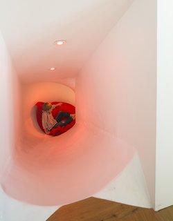 A Custom, LED-Lit Slide Twists Through This Family-Friendly Vacation Home - Photo 6 of 11 - It took a craftsman two weeks to shape the fiberglass gelcoat material into the shape of the slide, which connects a hallway off of the kitchen to the first-floor media room.
