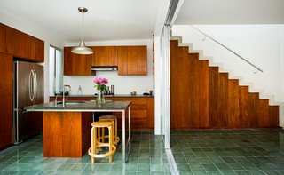 Handcrafted green cement tile floors are used in the kitchen and in many living spaces in the home. Honed granite counters, Tzalam wood cabinets, and GE Profile appliances complete the airy space above.
