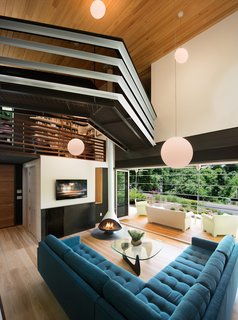 In the living room, Svenson opted for wide-plank ash floors and a fireplace from Malm. The room connects to the screened-in porch (accessed by folding doors) and has a view of the split-levels above. The jagged bridge leads to the residents' writing studios. "I wanted something that feels a little scary, that gives you energy when you walk across it," says Svenson.