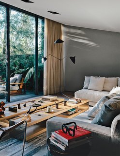 A Lush Retreat With a Sheltered Rooftop Pool in Mexico City - Photo 3 of 14 - Farca furnished the living room with a Serge Mouille three-arm floor lamp, custom sofas from EF Collection, and Surface tables by Vincent Van Duysen for B&B Italia.
