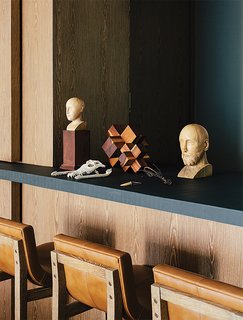 A Lush Retreat With a Sheltered Rooftop Pool in Mexico City - Photo 13 of 14 - In the dining room, antique wooden busts and a machiche cross designed by Farca are arranged on a resin countertop by Monica Calderon. The bar conceals a service area with an espresso machine.