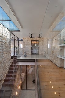 The original home was built in the shape of the Hebrew letter "Chet," which wrapped around an open courtyard. The courtyard was closed off to become flexible public space, and now lies in between two private living areas. A steel and wood bridge connects the private wings of the home, which consist of bedrooms, bathrooms, and working spaces for the residents.