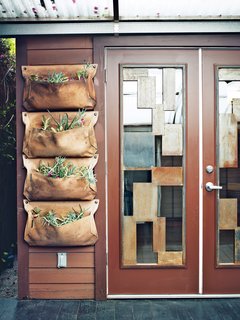 The area includes a Wally planter from Woolly Pocket near the custom steel-and-glass doors.