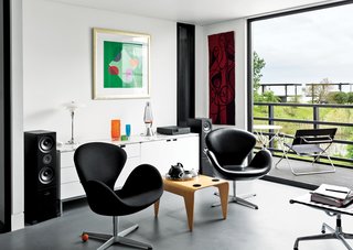 In the living room, Arne Jacobsen Swan chairs flank a Marcel Breuer for Isokon nesting table. Above the Florence Knoll–designed credenza is a print by English artist Terry Frost. The adjacent deck holds Breuer’s Folding Armchair and a table from Aram in London.