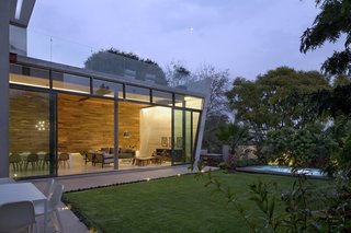 10 Retreats in Mexico For the Modernists Who Love the Outdoors - Photo 7 of 10 - Glass sliding doors allow the living and dining areas to open up to the garden, so that the family can easily entertain. "The living room and dinning room are lined in wood to give them a warm feeling in contrast to the concrete floor and ceiling," says Cesarman. The concrete wall features a chimney crafted of black granite for added visual interest.