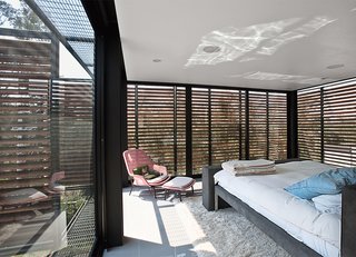 The master bedroom is shaded by exterior slats in cumaru, a sustainable tropical wood. Alazraki designed the custom bed frame.