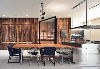 A vintage Lightolier pendant and sleek Arclinea cabinets by Antonio Citterio stand out against a wall paneled in reclaimed pine in the kitchen. Seating is a mix of Bertoia wire chairs and armchairs by the Mexican designer Hector Esrawe.