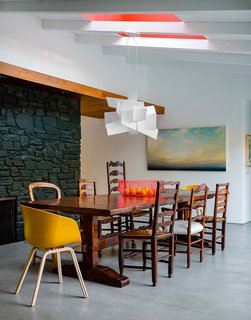 Walnut panels and touches of bright colors warm up the minimalist space, which the owners wanted to be "clean, eclectic, and modern." The pendant is Big Bang by Foscarini.