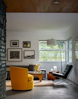 In the living room, the architects painted the limestone fireplace a dark shade of blue-green. The walnut coffee table is by Noguchi for Herman Miller. The Barcelona chair is by Mies van der Rohe.