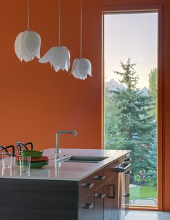 A Fun, Cost-Conscious Home With Bright Interiors and a Climbing Wall - Photo 4 of 9 - A polished chrome faucet from Kohler’s Purist collection enhances the kitchen. Walls and ceilings are made of drywall and painted brilliant hues that complement the home's industrial exterior.