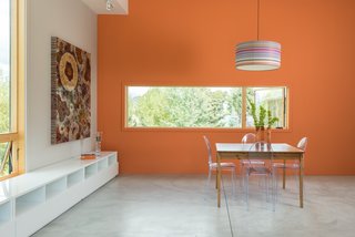 A Fun, Cost-Conscious Home With Bright Interiors and a Climbing Wall - Photo 5 of 9 - Made of stainless steel and TEKA hardwood, a Curzon dining table by Modloft is surrounded by a quartet of Victoria Ghost dining chairs by Philippe Starck for Kartell. A striped Missy pendant light by Filipe Lisboa hangs overhead. Four Chill White media consoles from CB2 line the western wall.